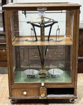 A set of cased Oertling scientific scales in glazed case. 25" high. One drawer lacking.