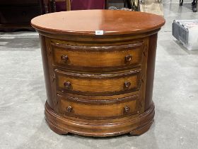 A chest of drawers of oval form.