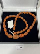 A necklace of graduated amber beads. 64g. 30" long.