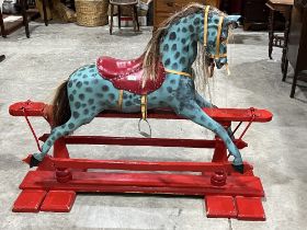 A carved painted rocking horse on baluster turned trestle base. The trestle 54" long.