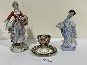 A Derby eggcup on integral stand and two Continental figures.