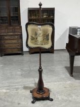 An early Victorian rosewood polescreen with needlework banner, on faceted baluster column and