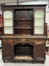 A Victorian oak dresser, the upper part with two glazed cupboards flanking two shelves, over base