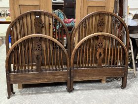 A pair of Heals 3' oak bedsteads with wheelback splats, side irons and slatted bases.