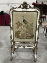 A Victorian parcel gilt gesso firescreen, the woolwork banner worked with a peafowl on a pedestal.