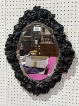 A 19th Century mirror with oval bevelled plate and embossed copper frame. 19½" high.