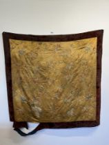 A 19th Century Oriental textile hanging, worked with foliage in coloured threads on a gold ground.