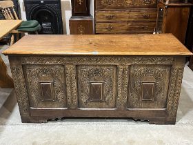 A joined oak chest with carved three panel fronts, raised on stiles. 58" wide.