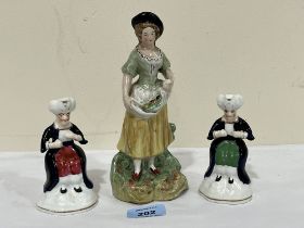 A 19th Century Staffordshire figure of a lady with fruit. 7¾" high, and a pair of smaller figures.