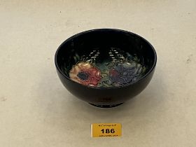 A Moorcroft bowl decorated with tube-lined flowers on a blue ground. 5¼" diam.