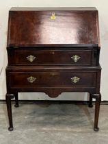 A walnut bureau on stand, the sloping fall over two drawers, on turned tapered legs with pad feet.