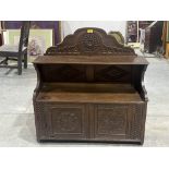 An oak mural cabinet enclosed by a pair of carved panel doors under a display shelf. 33" wide, c.