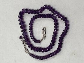 A necklace of amethyst beads with silver clasp. 20" long.