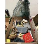 A box of fishing equipment including reels and flies.