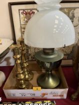 An oillamp and a pair of brass candlesticks.