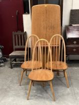 A set of three Ercol stickback chairs and a dining table.