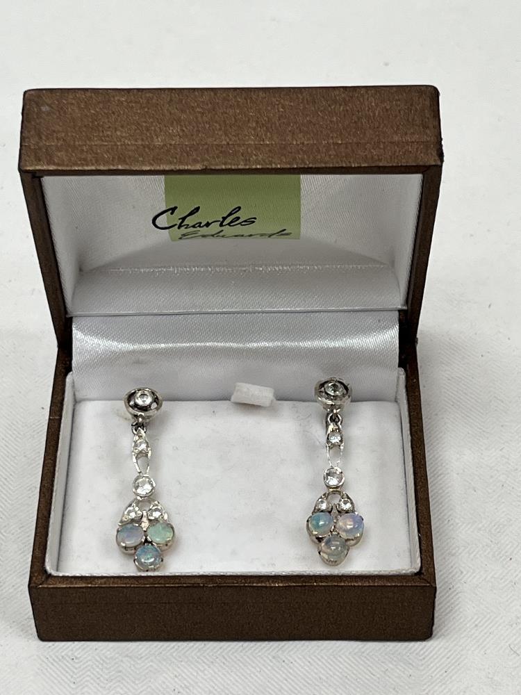 A pair of opal and white stone earrings.