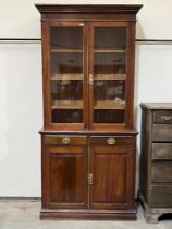 A Victorian walnut bookcase enclosed by a pair of glazed doors over a pair of drawers and conforming
