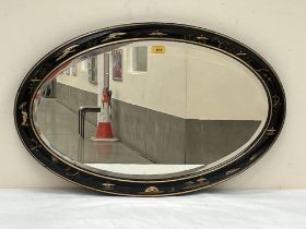 A lacquer framed oval wall mirror with bevelled plate, gilded and decorated with chinoiseries. 30"