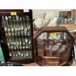 Two display cases, one containing a collection of plated crested spoons.