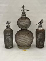 Three early glass and metal mesh applied soda syphons, the largest 20½" high.