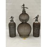 Three early glass and metal mesh applied soda syphons, the largest 20½" high.