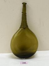 A 17th Century Persian glass saddle flask of amber green colour and typically flattened ovoid form