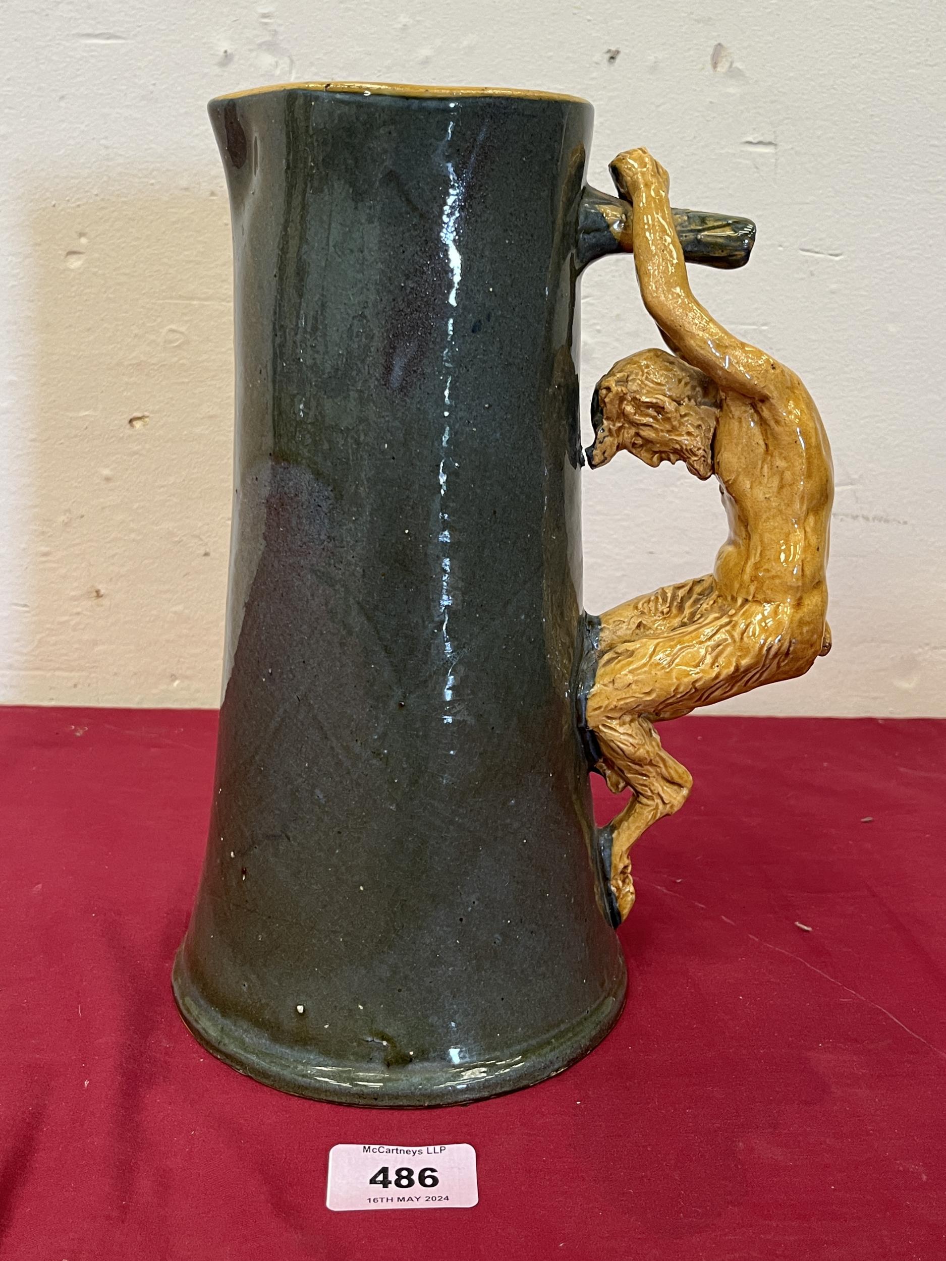 A green glazed pottery tapered cider pitcher with satyr handle in ocre glaze. 10½" high. Probably