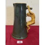 A green glazed pottery tapered cider pitcher with satyr handle in ocre glaze. 10½" high. Probably