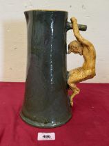 A green glazed pottery tapered cider pitcher with satyr handle in ocre glaze. 10½" high. Probably