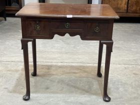 A George III mahogany lowboy with moulded top over three drawers, raised on turned tapered legs with
