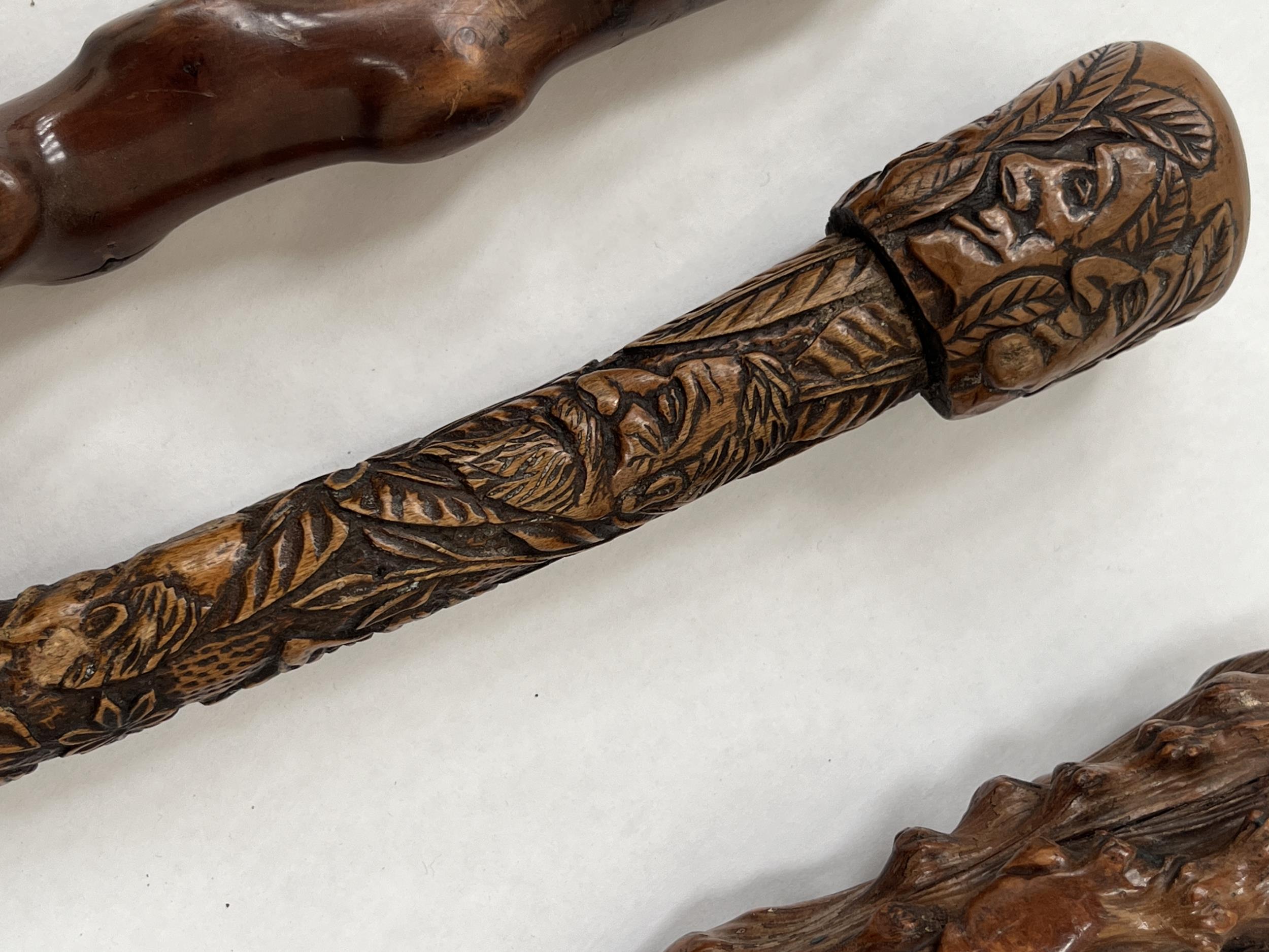 A 19th Century walking cane, the pommel and shaft carved with human heads and leafy foliage, 35" - Image 2 of 2