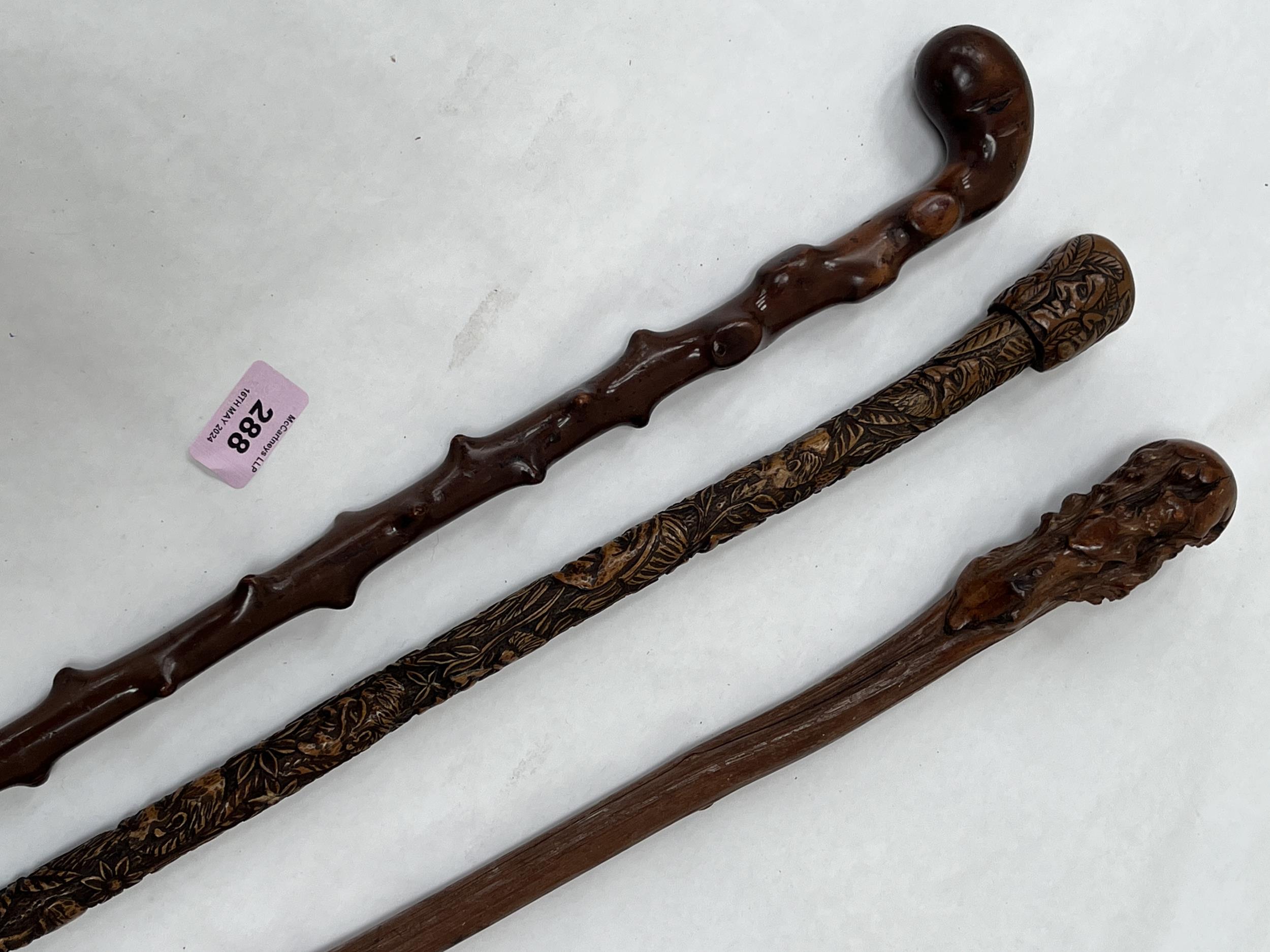 A 19th Century walking cane, the pommel and shaft carved with human heads and leafy foliage, 35"