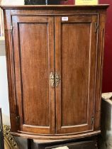 A George III oak bow-fronted hanging corner cupboard. 37" high.