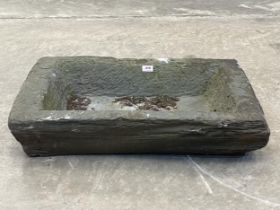 A Welsh slate trough of roughly hewn form. 28" x 18". Hole to base.