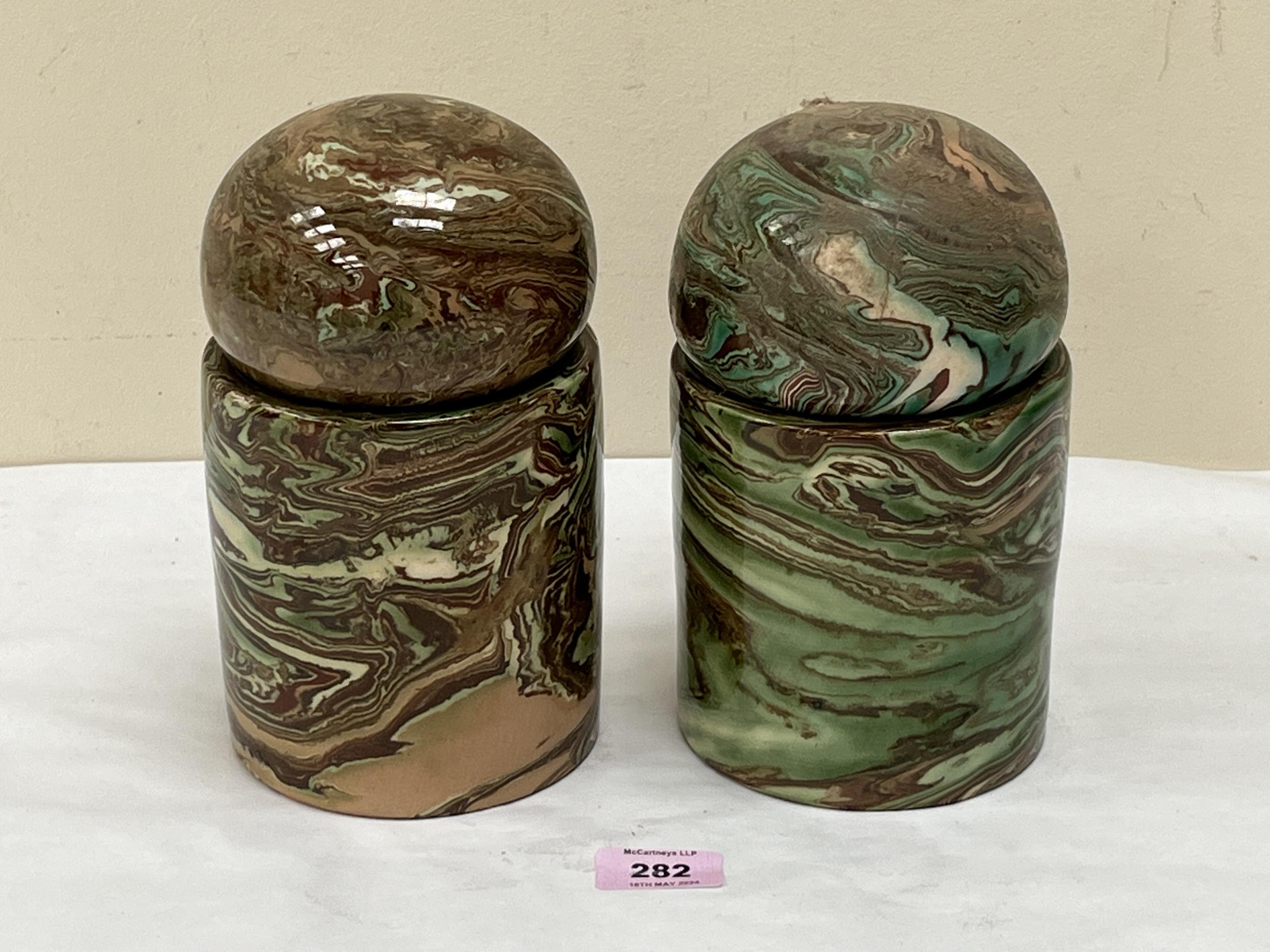 A pair of jars with globular covers, decorated with a marbled glaze in shades of green and brown.