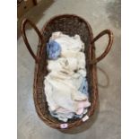 A wicker Moses basket with a collection of Victorian and later infant's clothes.