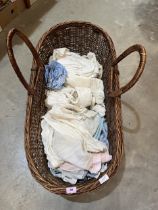 A wicker Moses basket with a collection of Victorian and later infant's clothes.