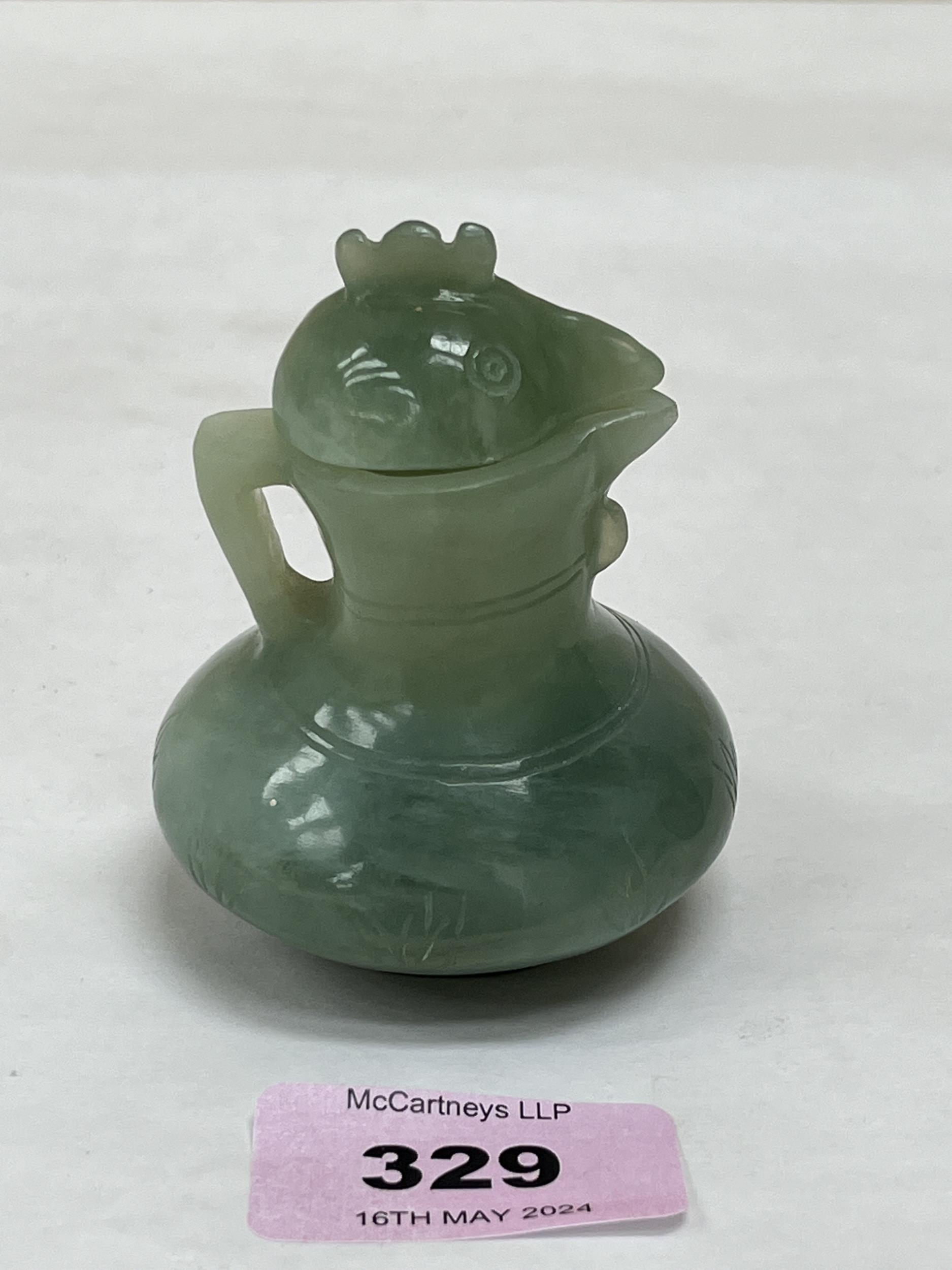 A Chinese green jade jug and cover, carved in the form of a cockerel. 3" high.