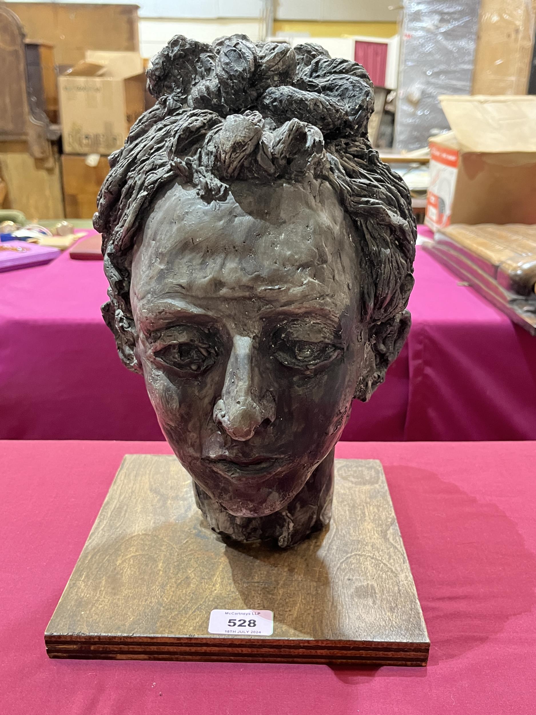 A ceramic composition sculpture of a female head on wood stand. 13" high.