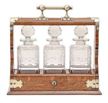 An EPNS mounted oak tantalus, early 20th c, with set of three cut glass decanters and stoppers, key,