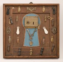 A display board of a Victorian brass door lock and brass, art metal, wood and pottery escutcheons
