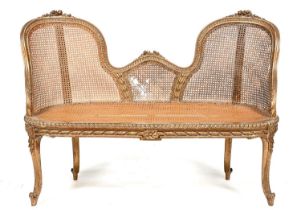 A French giltwood and caned settee, c1900, in Louis XV style, of twin chair back design, the moulded