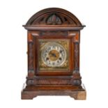 A German carved oak arch top bracket clock, c1930, with brass and silvered dial, pendulum and key,