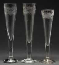 One and a pair of engraved glass flutes, 19th c, with grapevine or other border, 20 and 22cm h