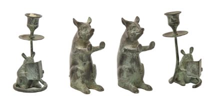 A pair of bronzed metal zoomorphic novelty candlesticks and a similar pair of seated pig sculptures,