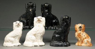 Three Staffordshire black glazed earthenware models of spaniels, one with glass eyes and three