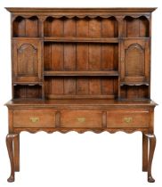 An oak dresser, early 19th c and later, the boarded rack with spice cupboards, the base with