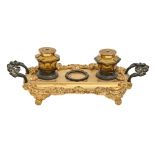 A Victorian gilt and patinated brass inkstand, cast with satyr masks, retaining the pair of original