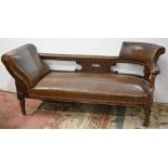 A Victorian carved mahogany couch, covered with nailed back brown leather, on turned legs and